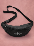 Riñonera Calvin Klein Jeans negra con correa ajustable, vista 1 sobre fondo rosado