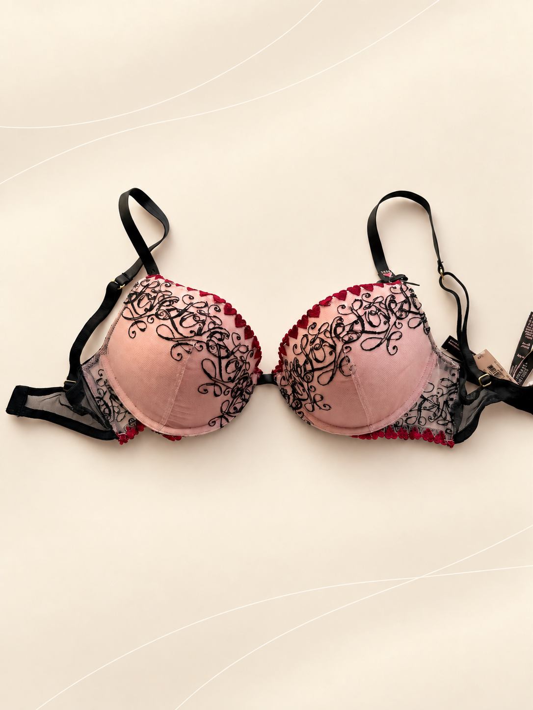 Corpiño V'S Push Up Rosa con Bordado Negro y Detalles Bordó, vista frontal sobre fondo crema de líneas suaves