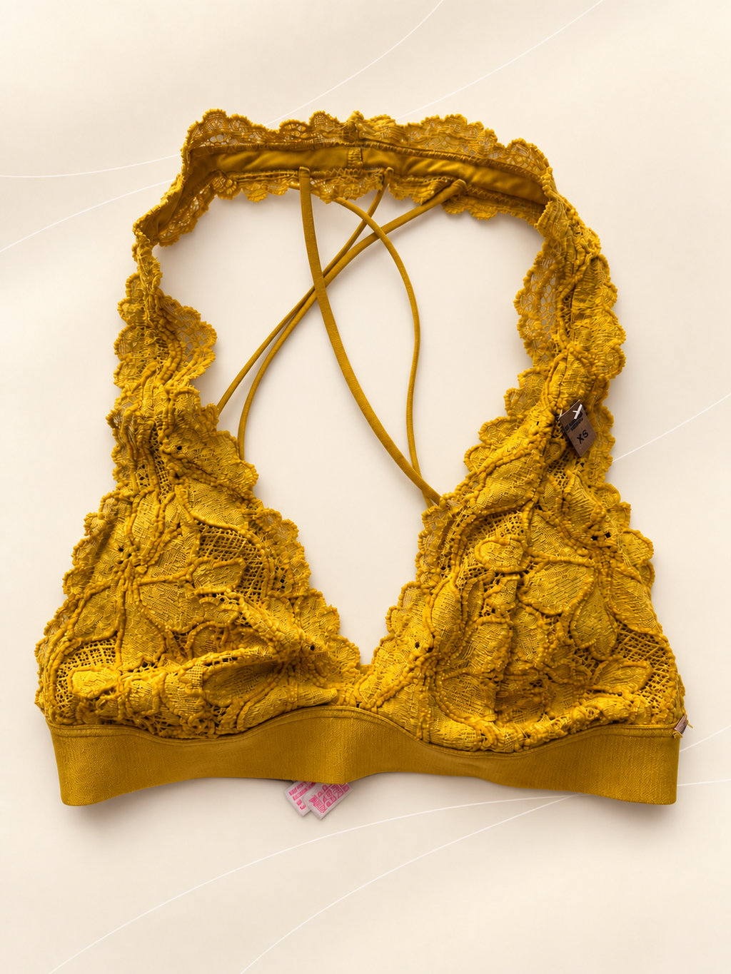 Bralette V'S de Encaje Mostaza con Tiras Cruzadas, vista frontal sobre fondo crema de líneas suaves