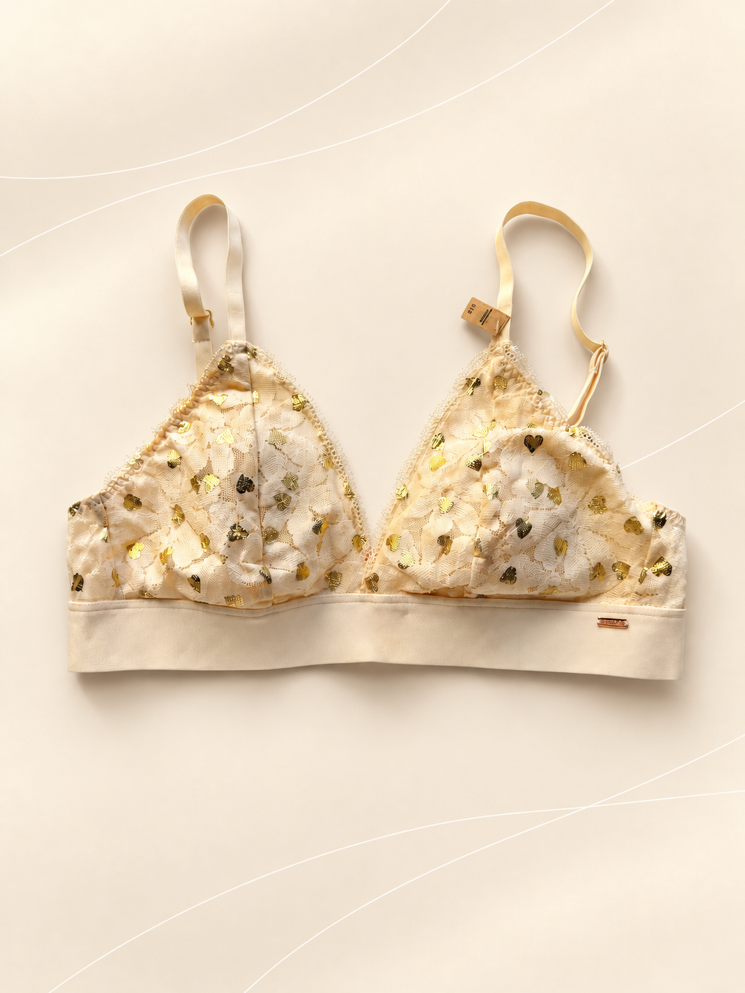 Bralette V'S de Encaje Marfil con Corazones Dorados, vista frontal sobre fondo crema de líneas suaves
