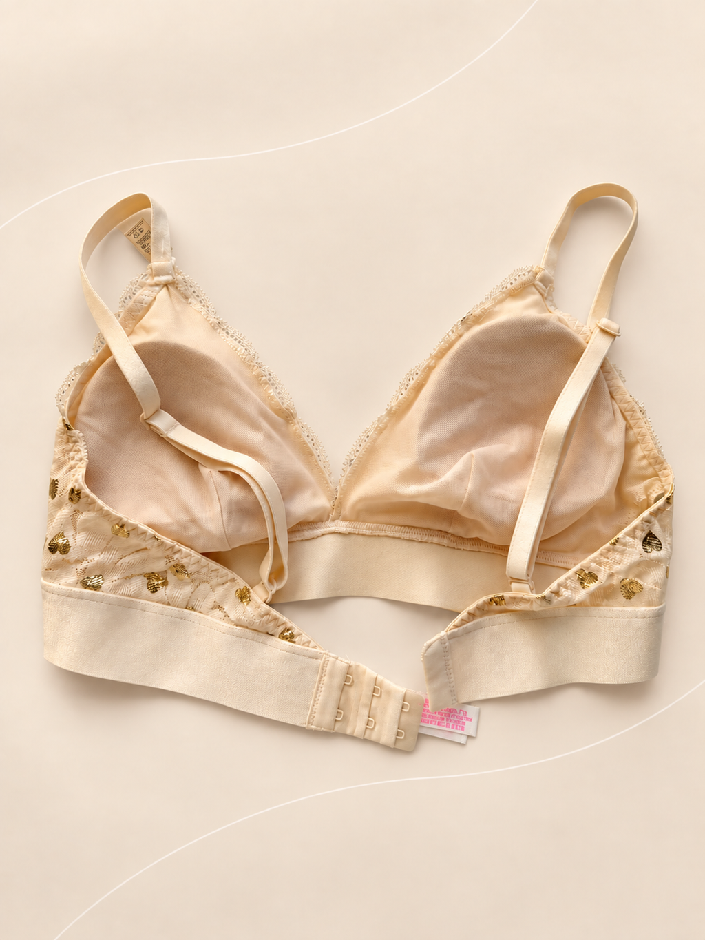 Bralette V'S de Encaje Marfil con Corazones Dorados, vista dorsal sobre fondo crema de líneas suaves