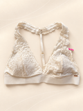 Bralette V'S de Encaje Blanco con Espalda Racerback, vista frontal sobre fondo crema de líneas suaves