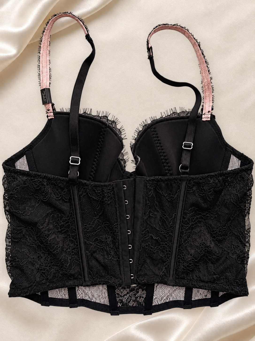 Bustier Negro de Encaje con Aro y Detalle Cruzado, vista dorsal sobre fondo marfil