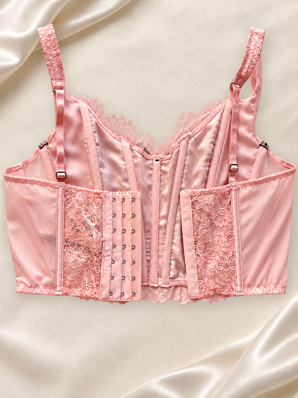Corset V'S Rosa de Encaje con Cordones Negros, vista dorsal sobre fondo marfil
