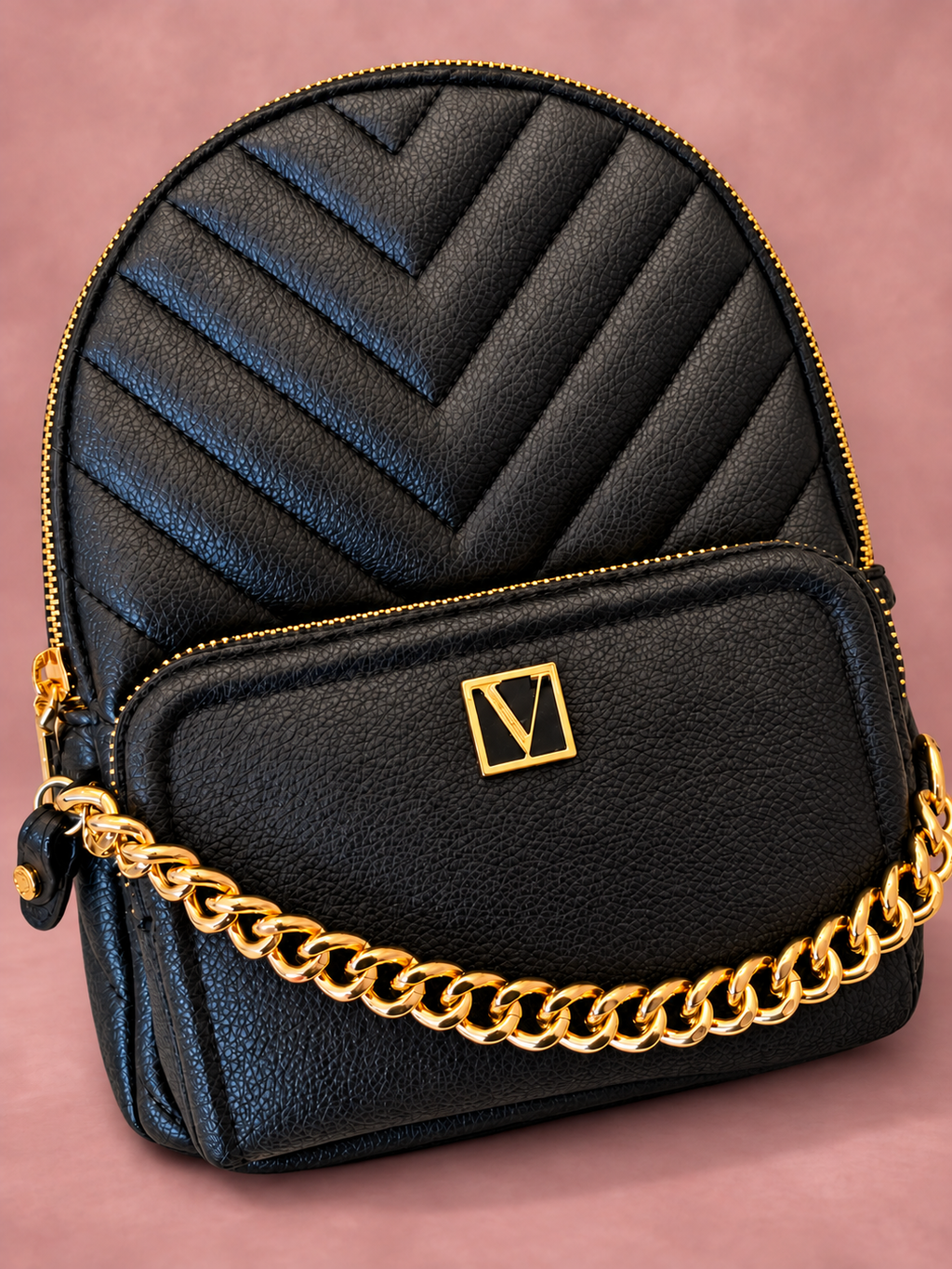 Mochila V'S negra con cadena dorada y sombra, vista 01