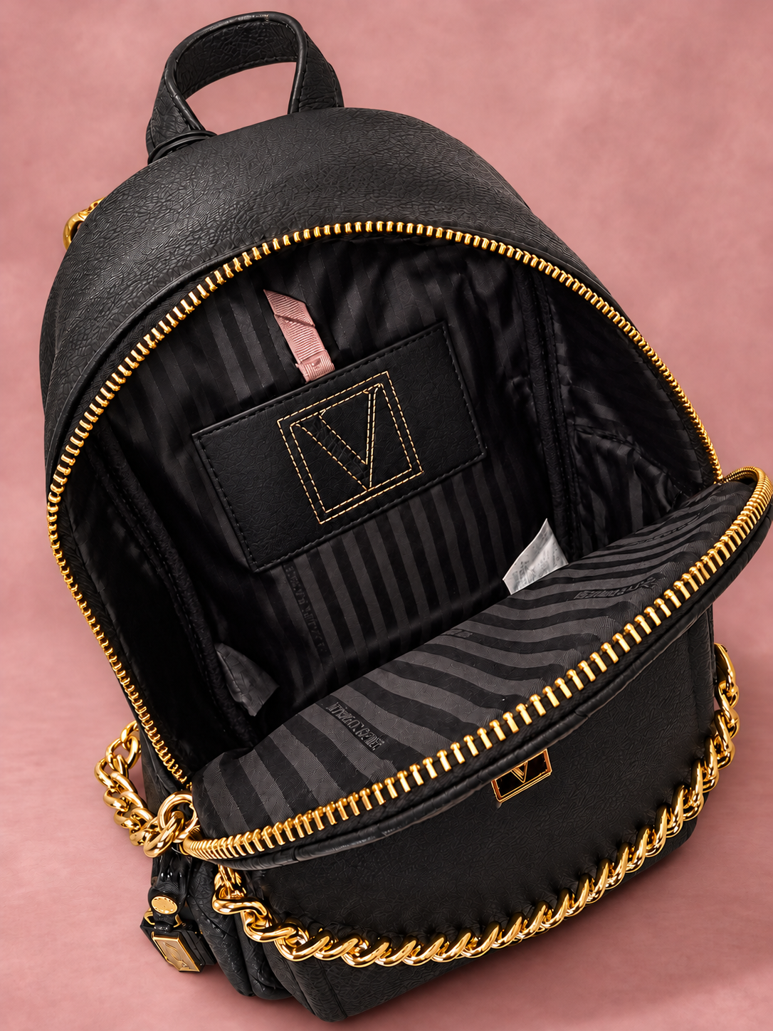 Mochila V'S negra con cadena dorada y sombra, vista 03