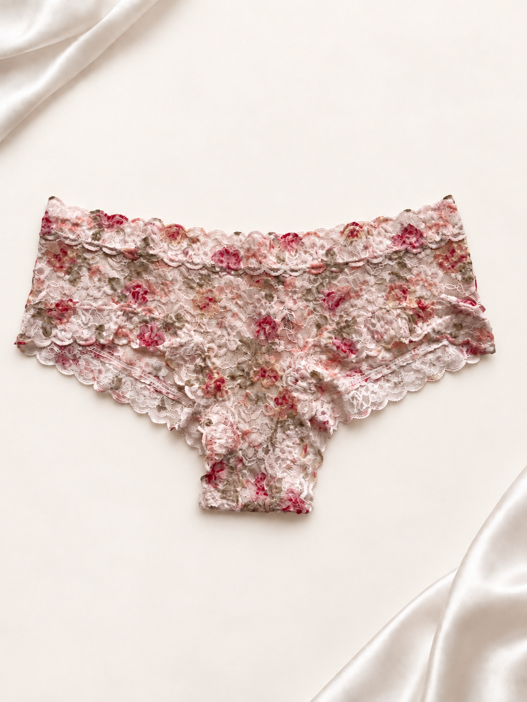 Panti de encaje blanco con estampado floral, vista frontal sobre fondo marfil