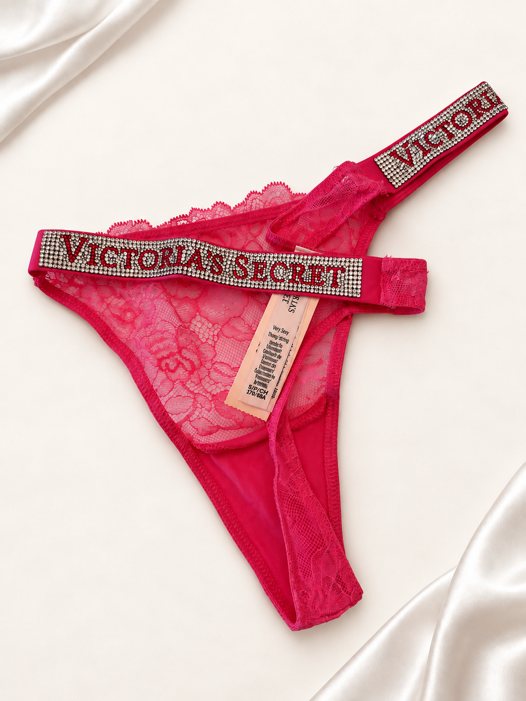 Panti V'S Rosa de Encaje con Tiras Logo Brillantes, vista dorsal sobre fondo marfil