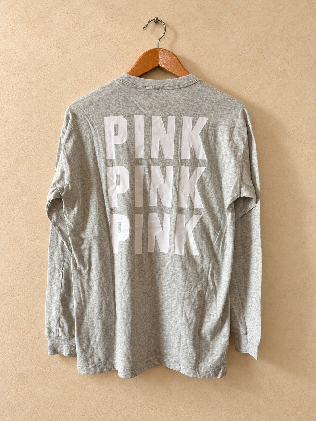 Dorso de Remera PINK Gris de Manga Larga con Logo Dorsal sobre fondo piedra cálida