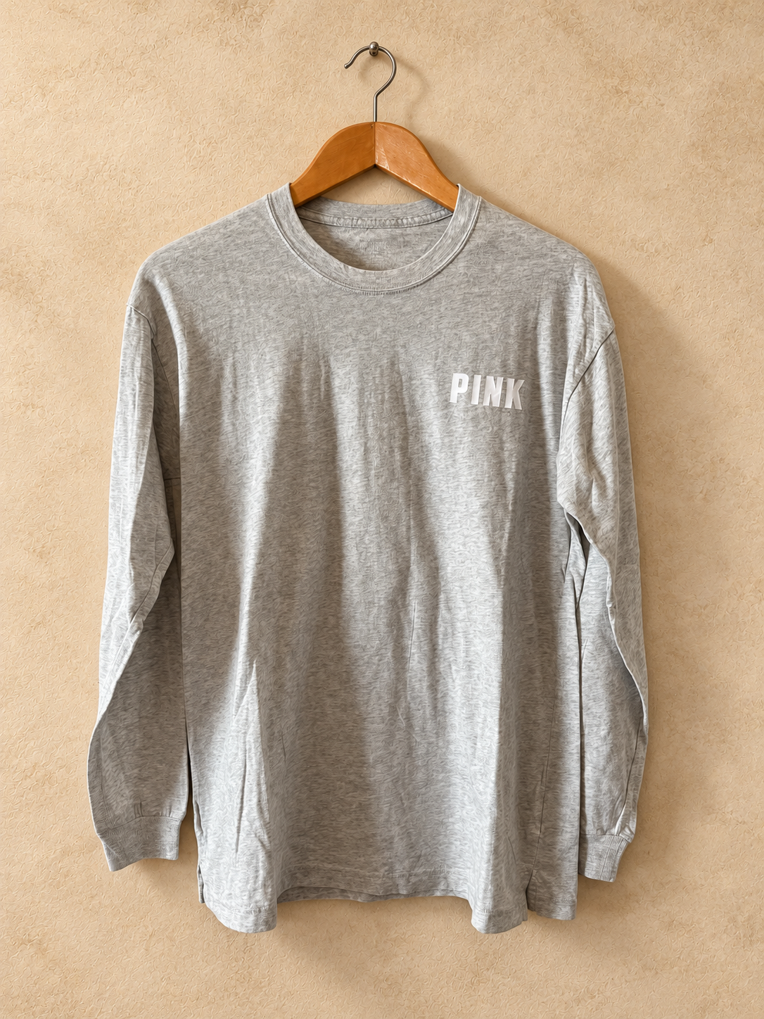 Frente de Remera PINK Gris de Manga Larga con Logo Dorsal sobre fondo piedra cálida