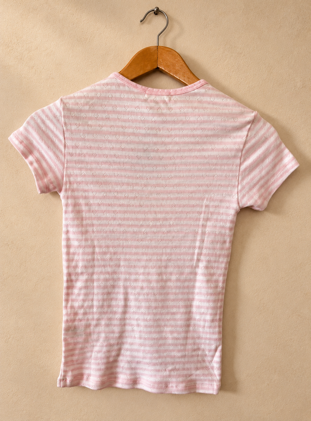 Dorso de Remera PINK Rosa y Blanca a Rayas con Microcorazones sobre fondo piedra cálida