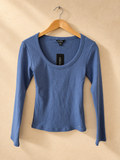 Frente de Remera GUESS Azul de Manga Larga con Escote Amplio sobre fondo piedra cálida