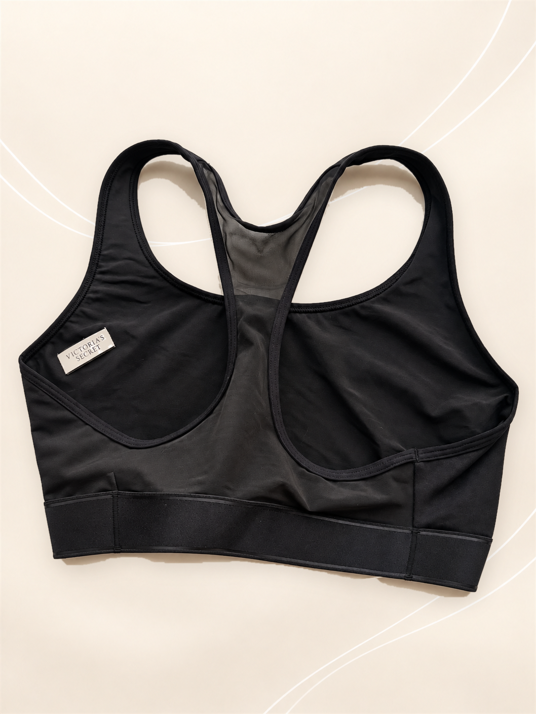 Corpiño Deportivo V'S Negro Racerback, vista dorsal sobre fondo crema de líneas suaves